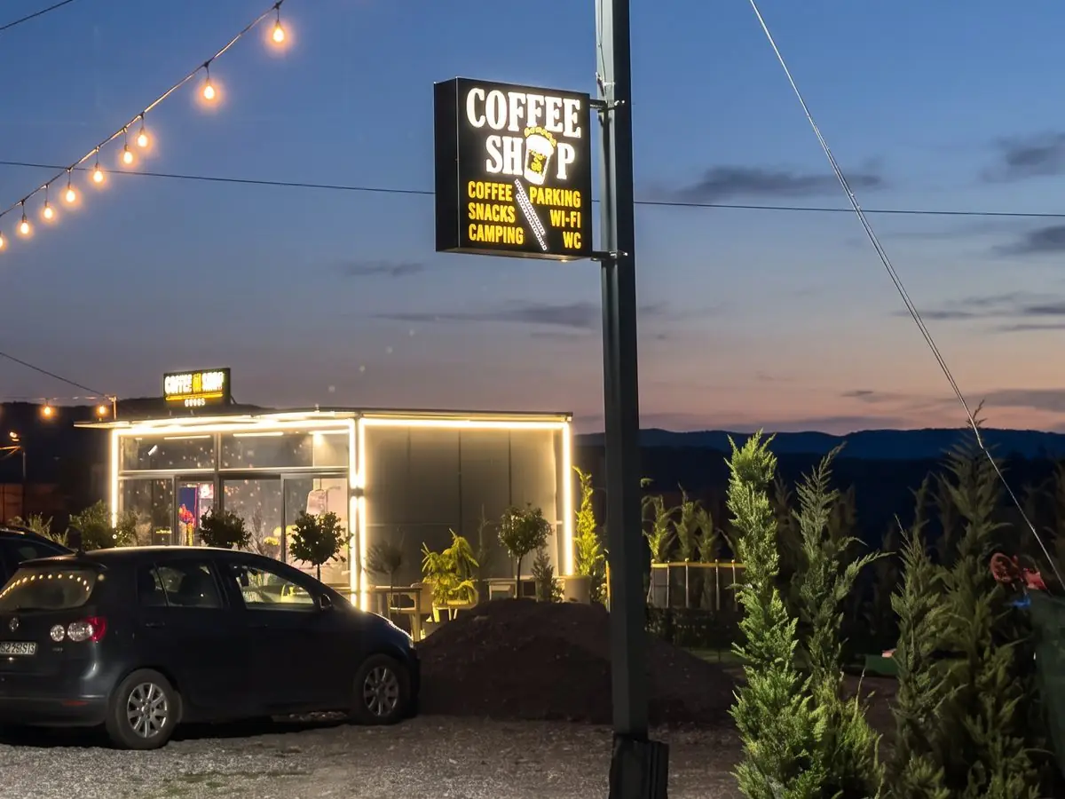 Cars parked at blue hour in front of the shop and its lit pole sign