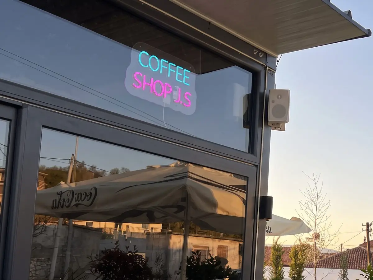 The terrace in the evening, with the COFFEE SHOP JS neon sign in the window